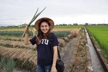 Student holding up plants in a agriculture field