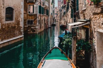 View looking over the front of a boat in a canal in Venice