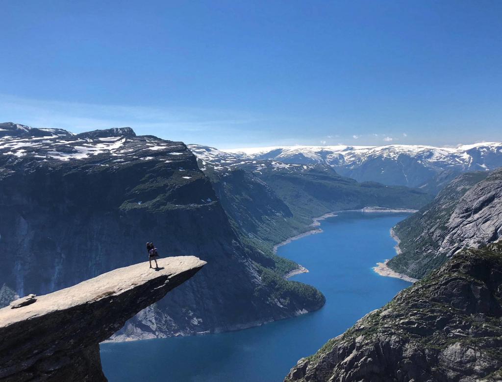 Standing on the edge of a rock in Trolltunga, Norway over glacial lake.