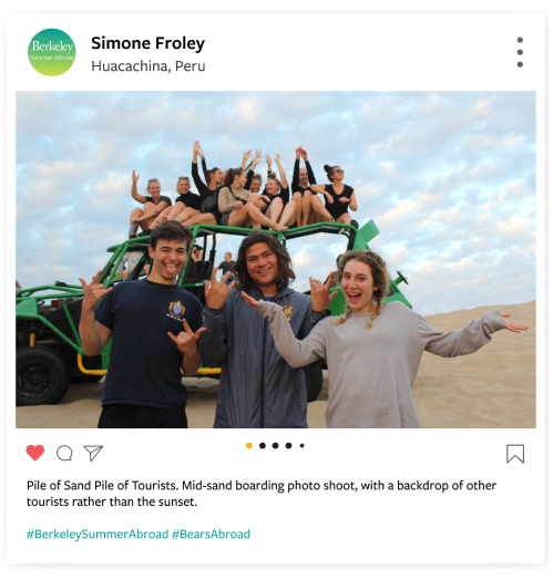 Group photo of students posing in front of a jeep, where they are taking a break form sand-boarding.