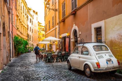 Alley in Italy with tables and a small white car.
