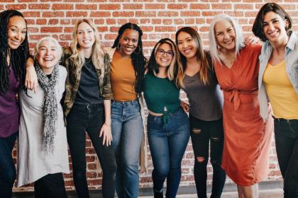 Group of women posing for a picture in front of a brick wall