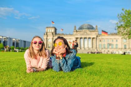 two students laying in a grass field in front of a building in Germany