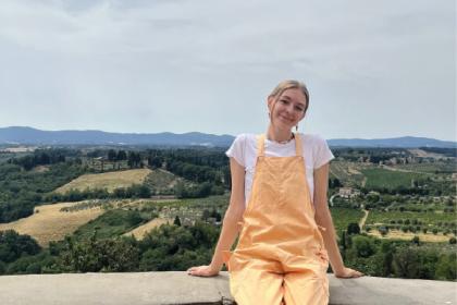 woman sitting on wall with green hills in the background