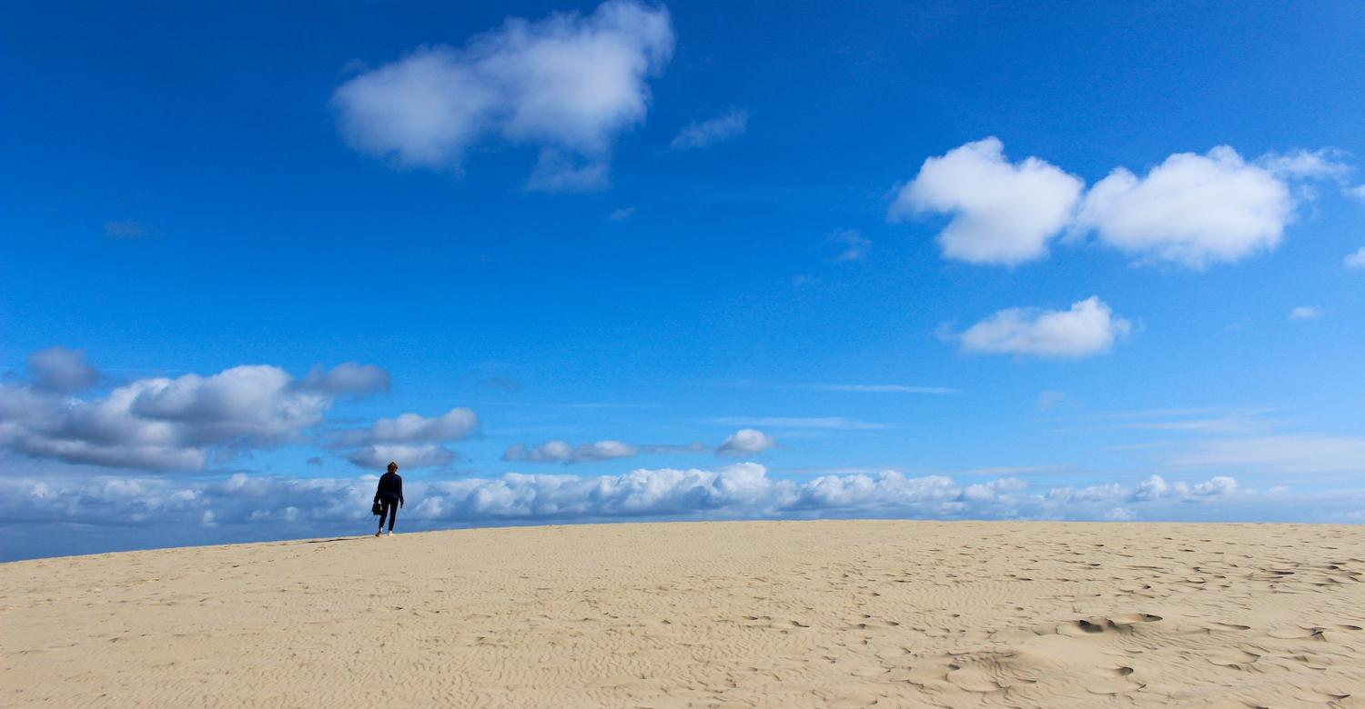 Person standing on sand under a bright blue sky