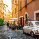 Alley in Italy with tables and a small white car.
