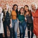 Group of women posing for a picture in front of a brick wall