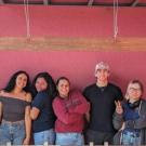 Students posing smiling in front of red cement wall